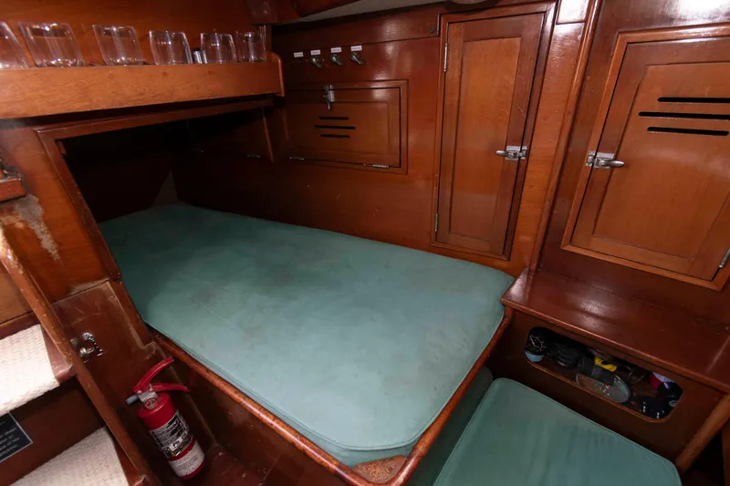Slide: The Image of Interior cabin of a 1979 Hinckley 43 Sloop with teal cushions and wooden paneling. - 16