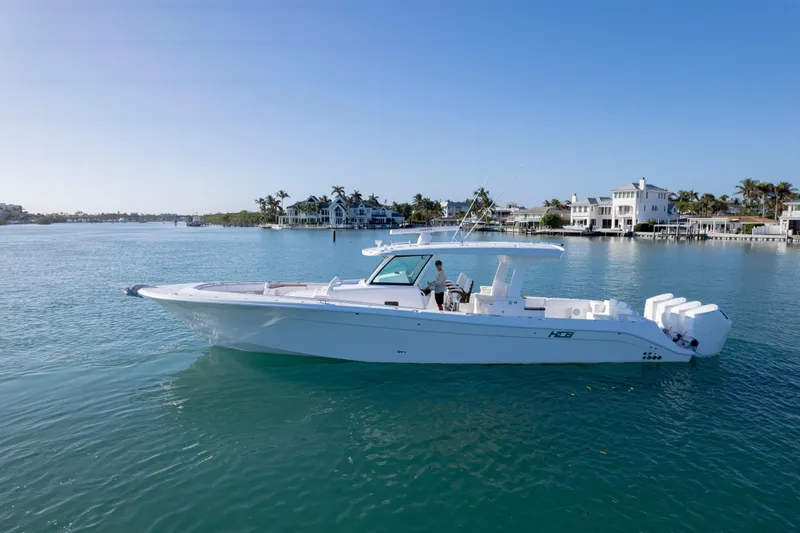 Slide: The Image of 2026 HCB 48 Campeon boat cruising on a sunny day near waterfront homes. - 47