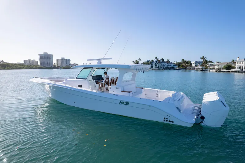 Slide: The Image of 2026 HCB 48 Campeon boat cruising on a sunny, calm waterfront with cityscape background. - 49