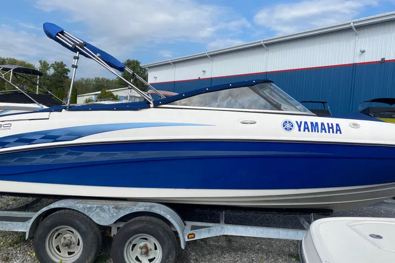 The Image of 2005 Yamaha Boats SX230 on trailer, blue and white design, parked outdoors. - 1