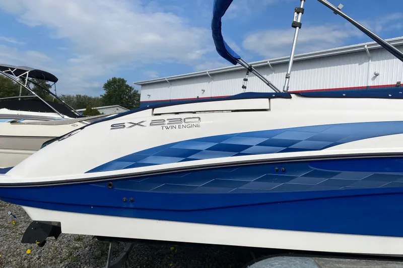 Slide: The Image of 2005 Yamaha Boats SX230 twin engine, blue and white design, parked outdoors. - 2