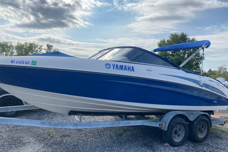 Slide: The Image of 2005 Yamaha Boats SX230 on trailer, blue and white, parked outdoors under cloudy sky. - 4