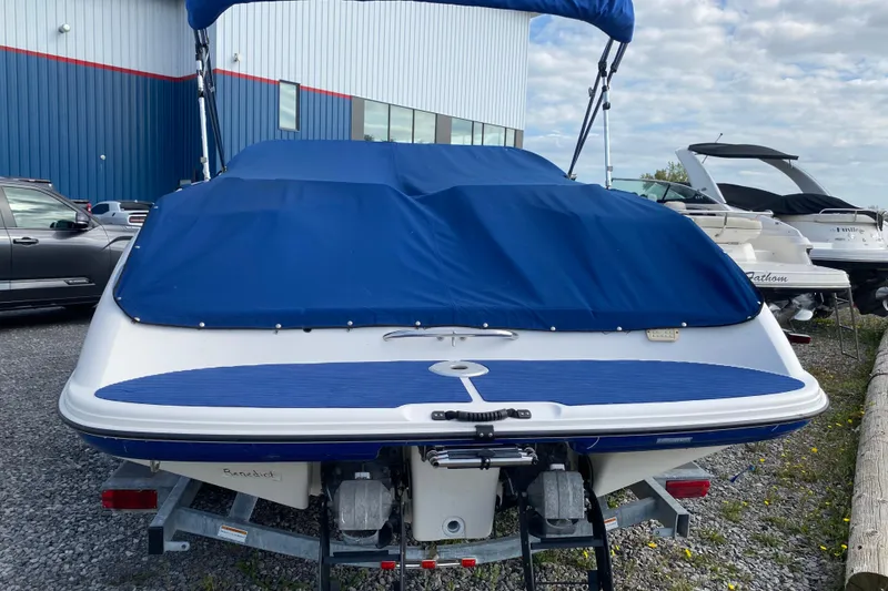 Slide: The Image of 2005 Yamaha Boats SX230 with blue cover, parked outdoors near other boats. - 6