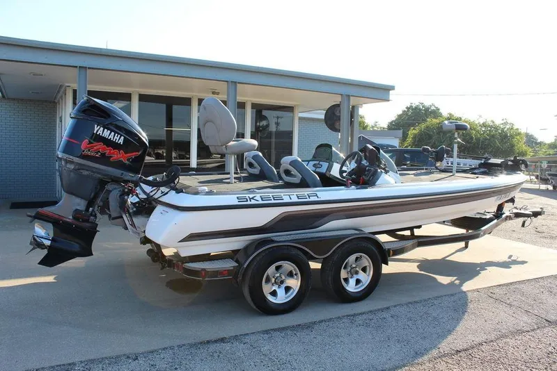 Slide: The Image of 2011 Skeeter ZX225 boat with Yamaha engine, parked on a trailer outside a building. - 4