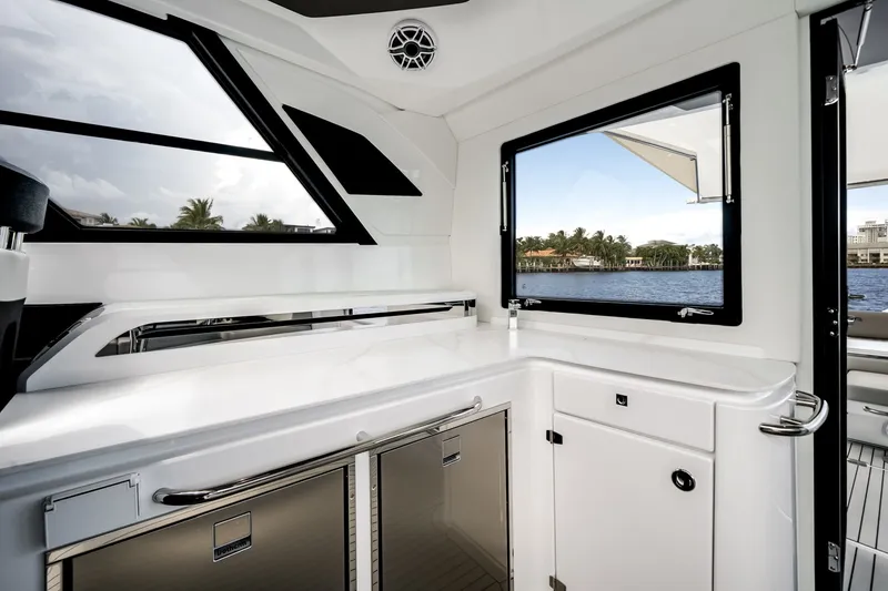 Slide: The Image of The modern galley of the Cruisers Yachts 50 GLS features white cabinetry and large windows overlooking the water. - 32