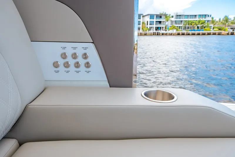 Slide: The Image of Armrest with built-in cup holder and control buttons, overlooking water and modern buildings. - 26
