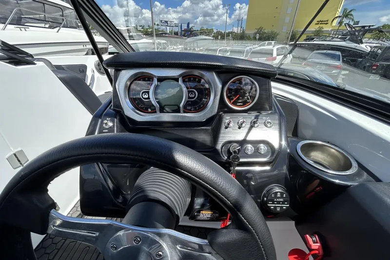 Slide: The Image of 2023 Scarab 255 ID boat dashboard with steering wheel and gauges, parked outdoors. - 20
