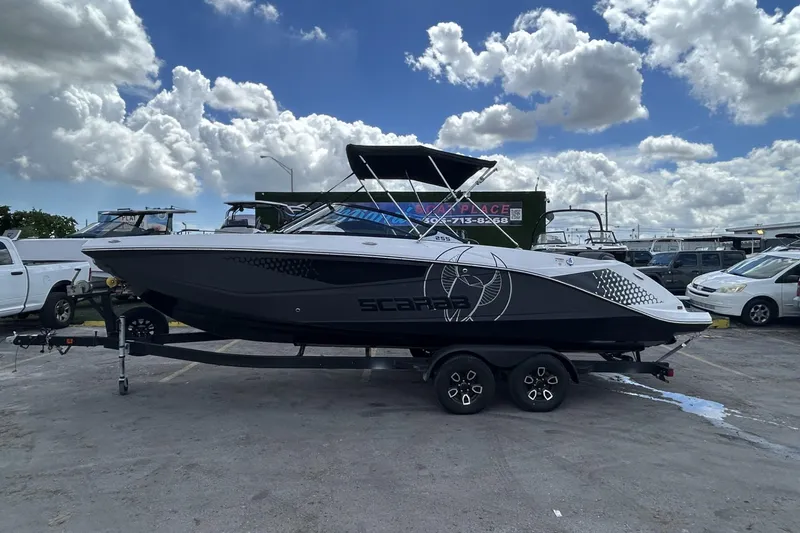 Slide: The Image of 2023 Scarab 255 ID boat on trailer under cloudy sky, parked in lot. - 24