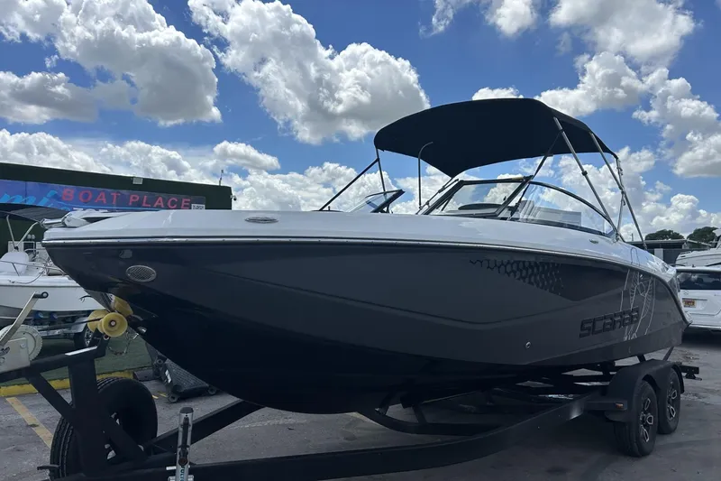 Slide: The Image of 2023 Scarab 255 ID boat with canopy on trailer under cloudy sky. - 48