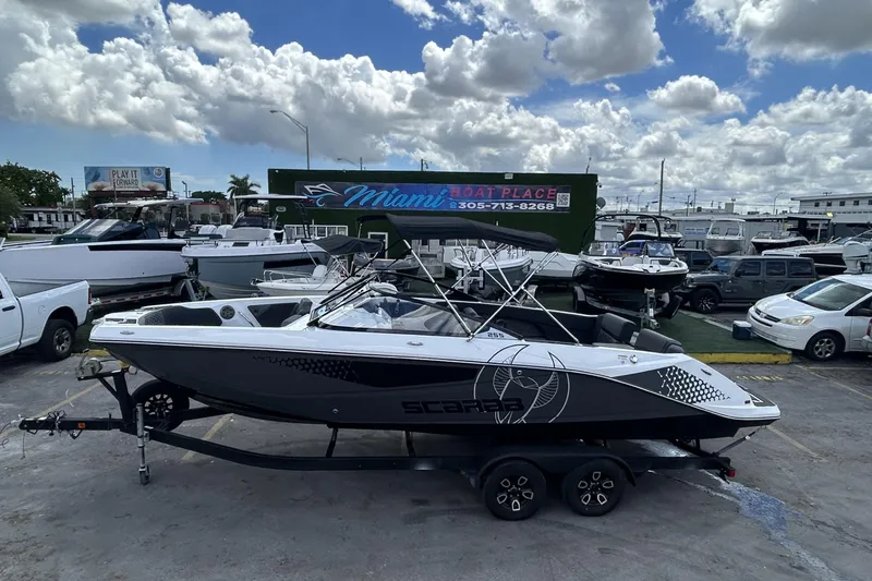 Slide: The Image of 2023 Scarab 255 ID boat on trailer at Miami Boat Place under cloudy sky. - 53