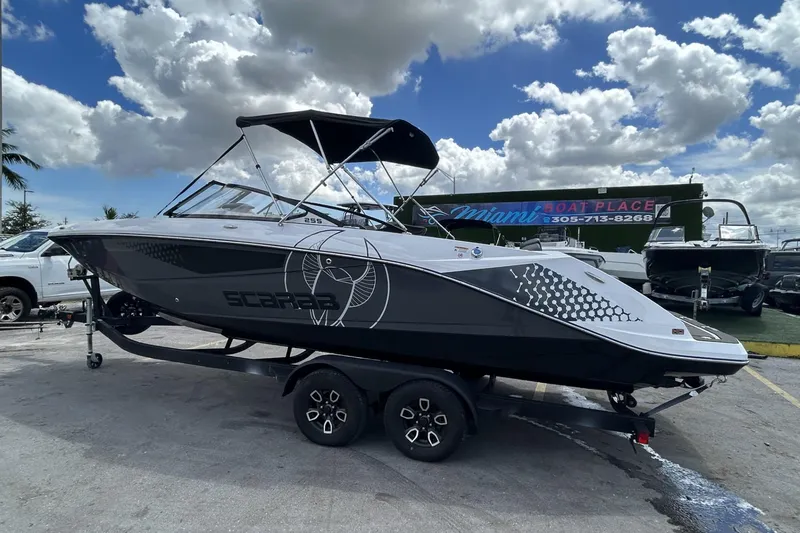 Slide: The Image of 2023 Scarab 255 ID boat on trailer under cloudy sky at Miami Boat Place. - 63
