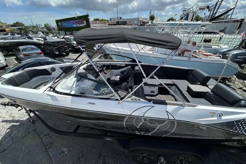 Slide: The Image of 2023 Scarab 255 ID boat with canopy, parked in a marina, surrounded by other boats. - 7