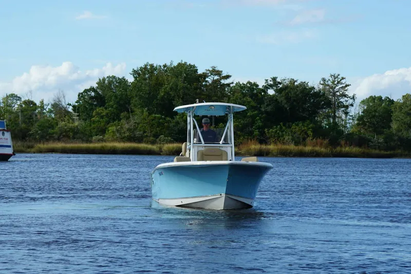 Slide: The Image of 2018 Sea Hunt Ultra 234 boat cruising on a calm river with lush greenery. - 15