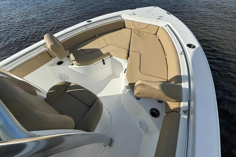 Slide: The Image of 2018 Sea Hunt Ultra 234 boat interior with tan seating on calm water. - 19