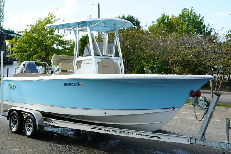 Slide: The Image of 2018 Sea Hunt Ultra 234 boat on trailer, light blue hull, parked outdoors. - 26