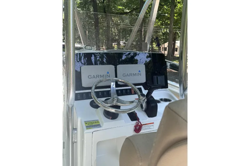 Slide: The Image of 2018 Sea Hunt Ultra 234 boat on a calm lake with trees in the background. - 7