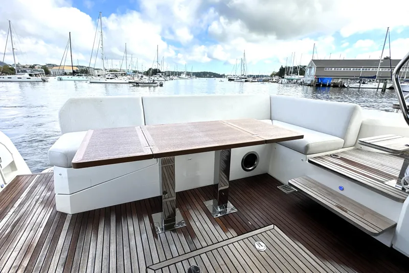 Slide: The Image of Outdoor seating area on 2023 Prestige 520 yacht with wooden table and marina view. - 12