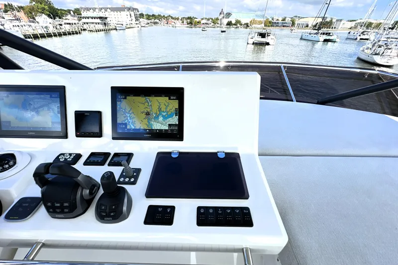 Slide: The Image of 2023 Prestige 520 yacht helm with navigation screens and controls, overlooking marina. - 28