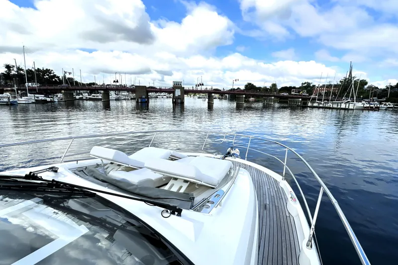 Slide: The Image of 2023 Prestige 520 yacht on calm waters near a marina and bridge. - 33