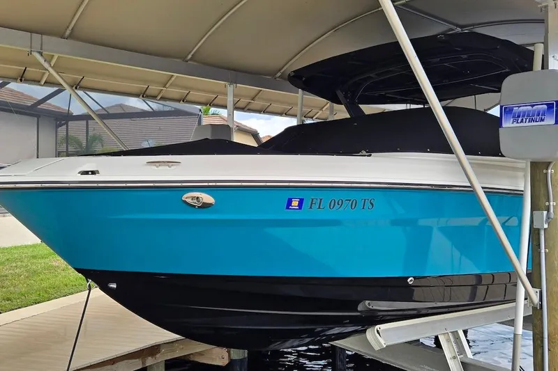 The Image of 2023 Sea Ray SLX 280 Outboard boat in blue, docked under a canopy. - 0