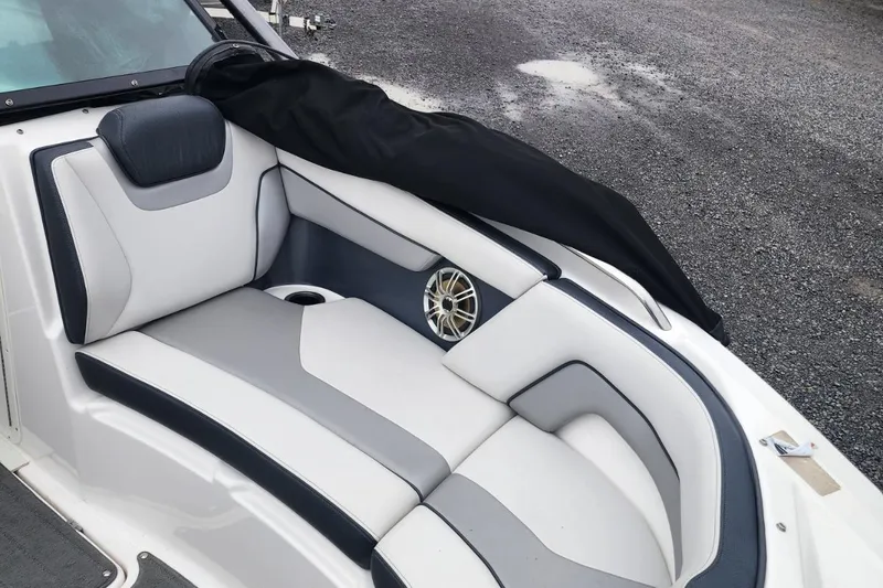 Slide: The Image of 2015 Yamaha Boats 212X interior with white and gray seating, speaker, and cup holder. - 16