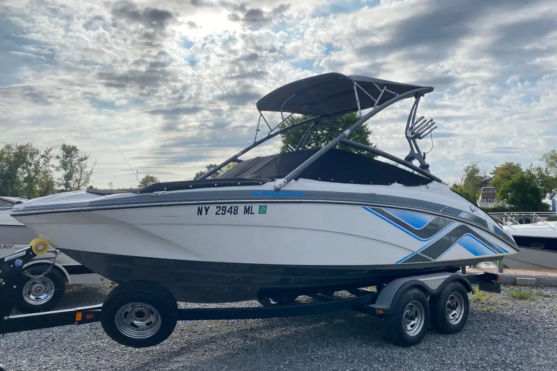 Slide: The Image of 2015 Yamaha Boats 212X on trailer under cloudy sky, side view. - 2