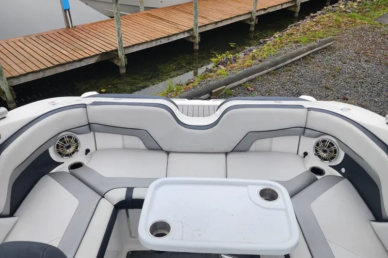 Slide: The Image of 2015 Yamaha Boats 212X interior with seating, table, and speakers near dock. - 29