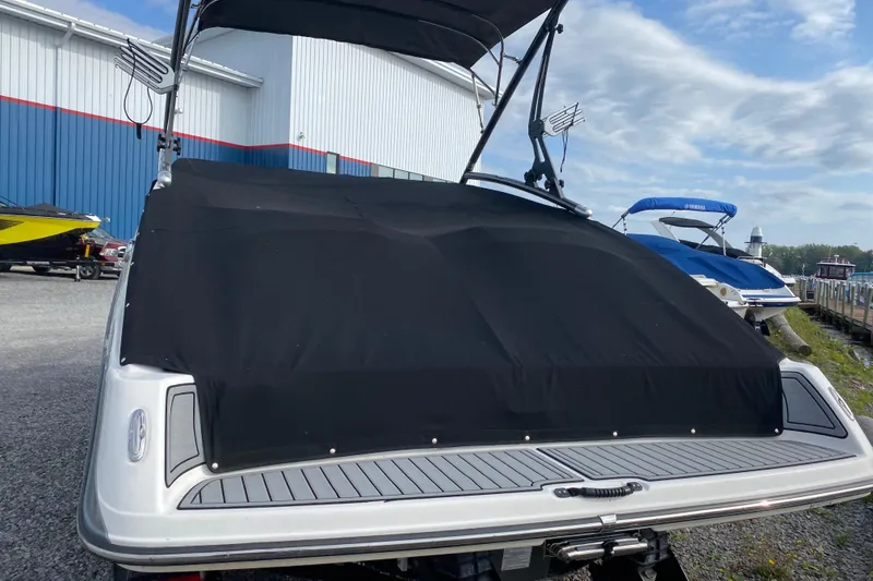 Slide: The Image of 2015 Yamaha Boats 212X with black cover, docked near blue and white buildings. - 5