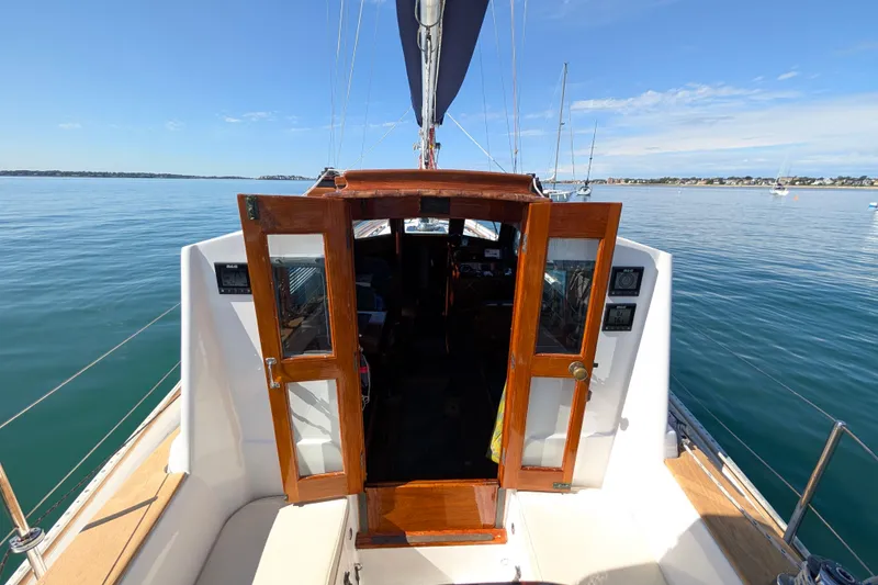 Slide: The Image of 1982 Shannon Pilothouse sailboat with open cabin doors on calm water. - 14