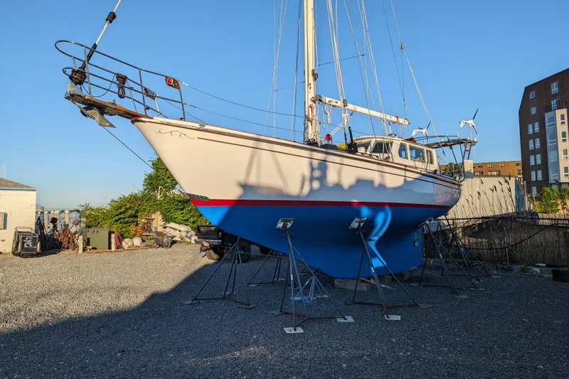 Slide: The Image of 1982 Shannon Pilothouse sailboat on stands in a gravel yard, under clear blue sky. - 18