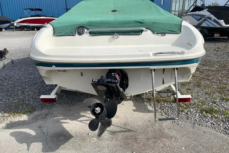 Slide: The Image of 1999 Ebbtide 2300 Bow Rider boat with green cover, rear view showing propeller and ladder. - 4