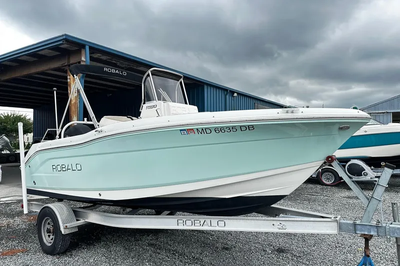 The Image of 2017 Robalo R180 Center Console boat on trailer under cloudy sky. - 0