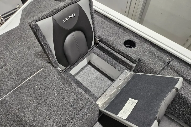 Slide: The Image of 2026 Lund 1875 Renegade boat interior with open storage compartment and cushioned seating. - 13