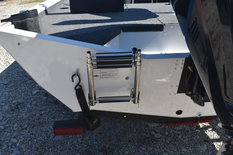 Slide: The Image of 2026 Lund 1875 Renegade boat stern with ladder and motor mount, on gravel surface. - 7
