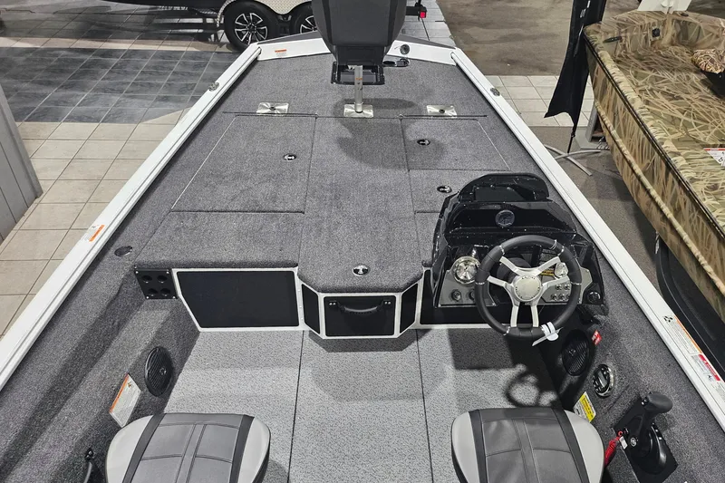 Slide: The Image of 2026 Lund 1875 Renegade boat interior with steering wheel and seating, displayed indoors. - 8