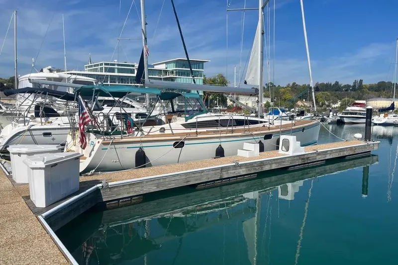 The Image of Sailboat Delphia 47, 2012 model, docked at a marina with clear blue skies. - 0