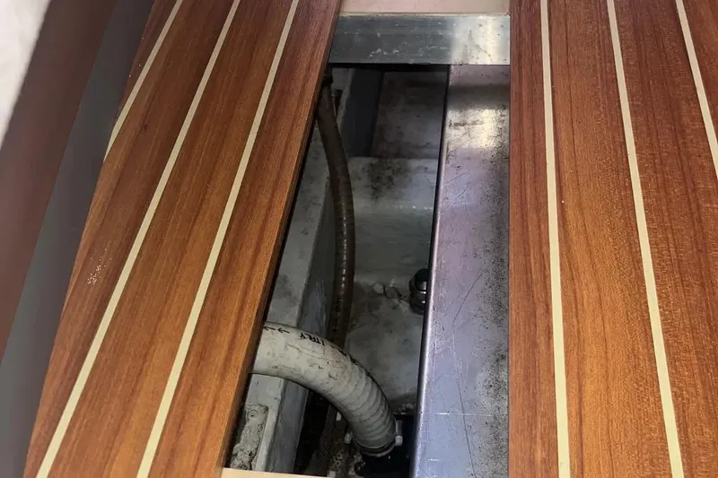 Slide: The Image of Wooden floor panel with visible piping in a 2012 Delphia 47 yacht interior. - 58