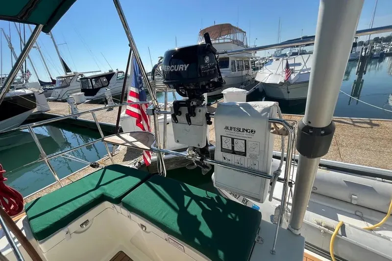 Slide: The Image of Delphia 47 sailboat cockpit with green cushions, Mercury motor, and Lifesling, docked at marina. - 7