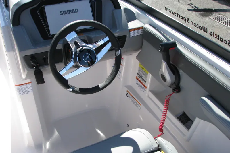 Slide: The Image of 2026 Chaparral 23 SSi OB boat cockpit with steering wheel and Simrad display. - 4