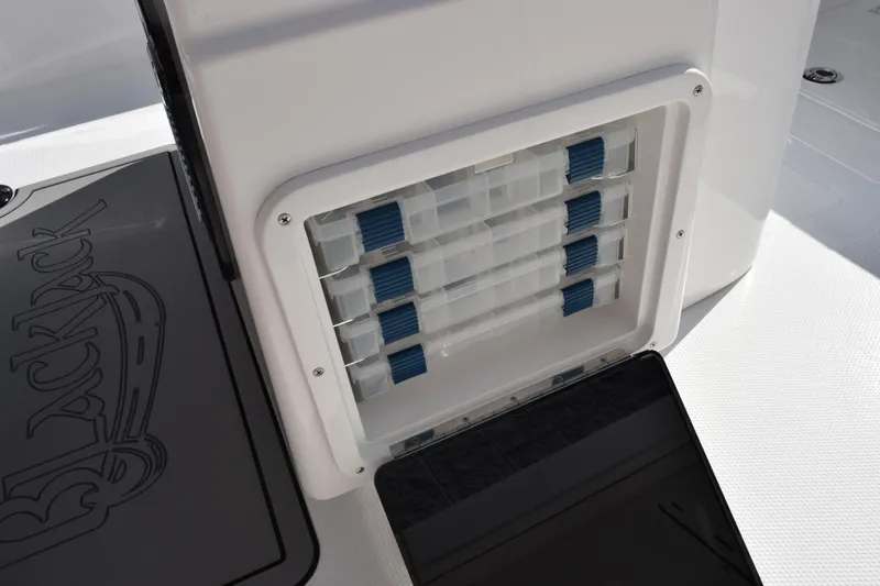 Slide: The Image of 2026 BlackJack 256 Coastal boat storage compartment with organized tackle boxes. - 17
