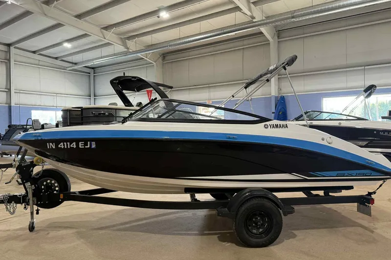 Slide: The Image of 2022 Yamaha Boats SX190 in showroom, sleek design, black and blue accents, on trailer. - 7