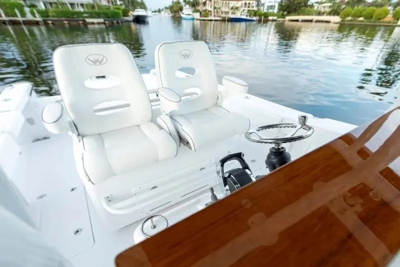 Slide: The Image of 2026 Southport 30 FE boat interior with white seating and steering wheel, docked on calm water. - 3