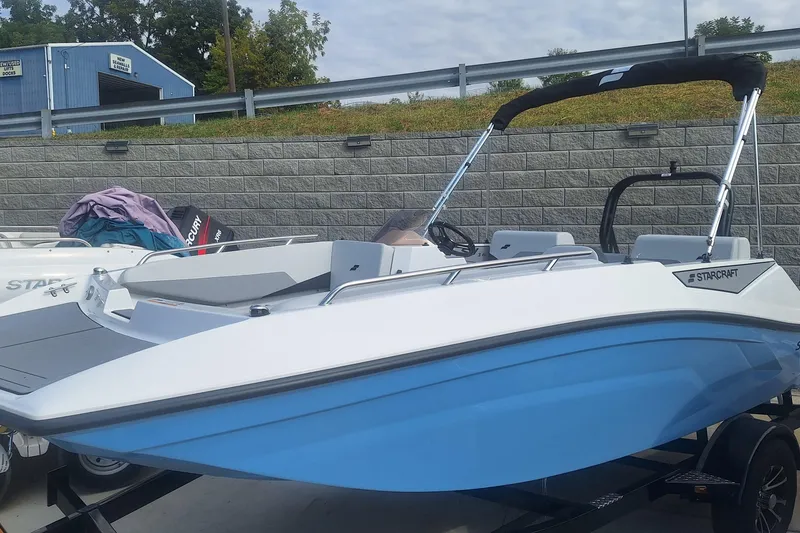 The Image of 2026 Starcraft SV 16 OB boat with blue hull and black canopy on trailer. - 0
