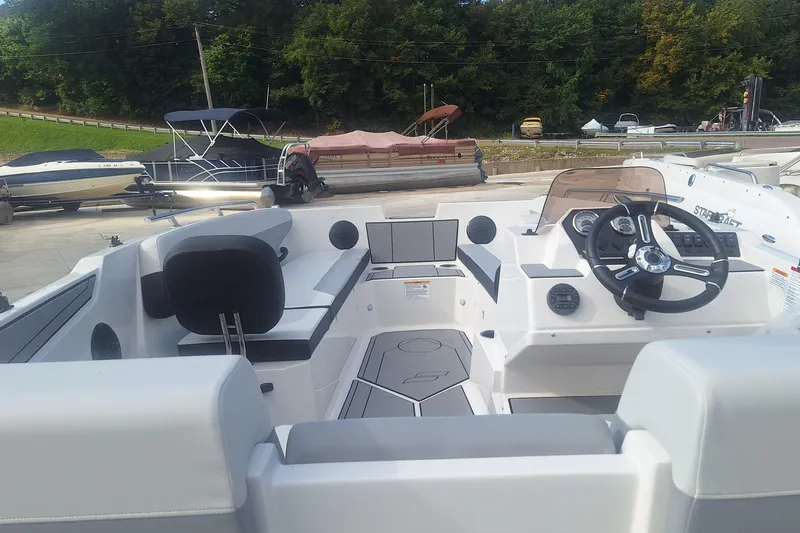 Slide: The Image of 2026 Starcraft SV 16 OB boat interior with steering wheel and seating, docked near other boats. - 2