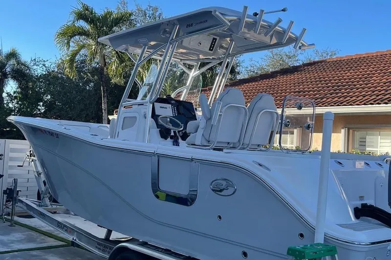 Slide: The Image of 2021 Sea Fox 268 Commander boat on trailer, parked near a house with palm trees. - 14