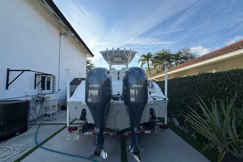 Slide: The Image of 2021 Sea Fox 268 Commander boat with dual Yamaha 200 engines, parked beside a house. - 2