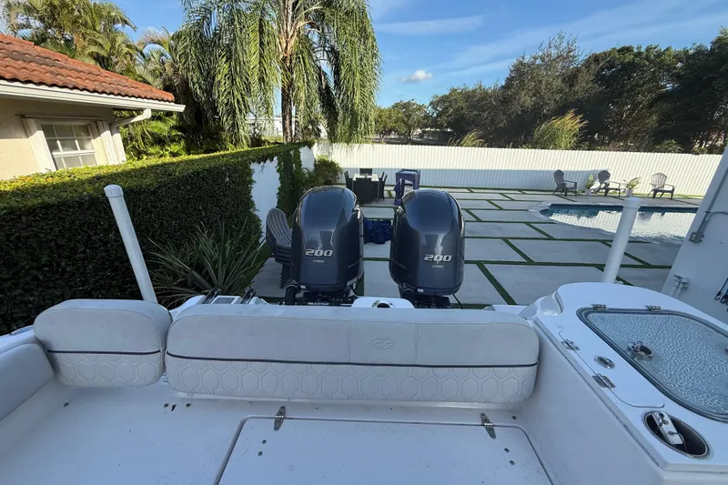 Slide: The Image of 2021 Sea Fox 268 Commander boat with dual 200 horsepower engines, parked near a poolside patio. - 28