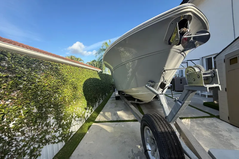 Slide: The Image of 2021 Sea Fox 268 Commander boat on trailer, parked beside a hedge under clear blue sky. - 63