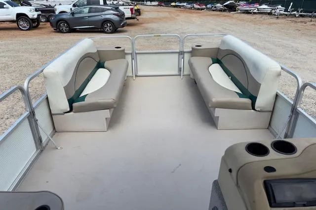 Slide: The Image of 1997 Grumman 24 FS pontoon boat interior with beige seating and cup holders. - 10
