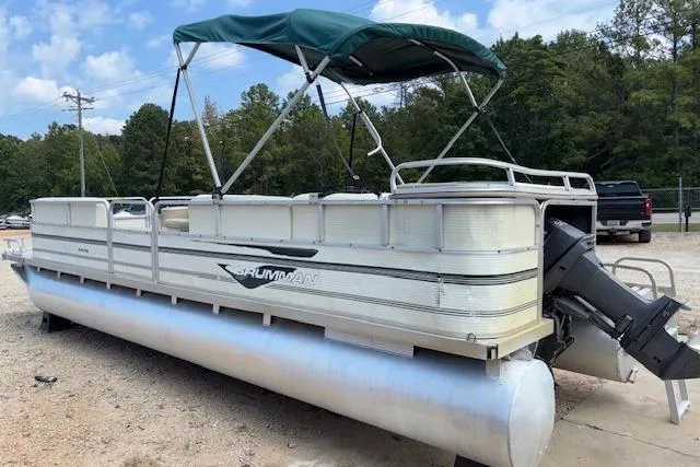 Slide: The Image of 1997 Grumman 24 FS pontoon boat with canopy, parked outdoors on a sunny day. - 4